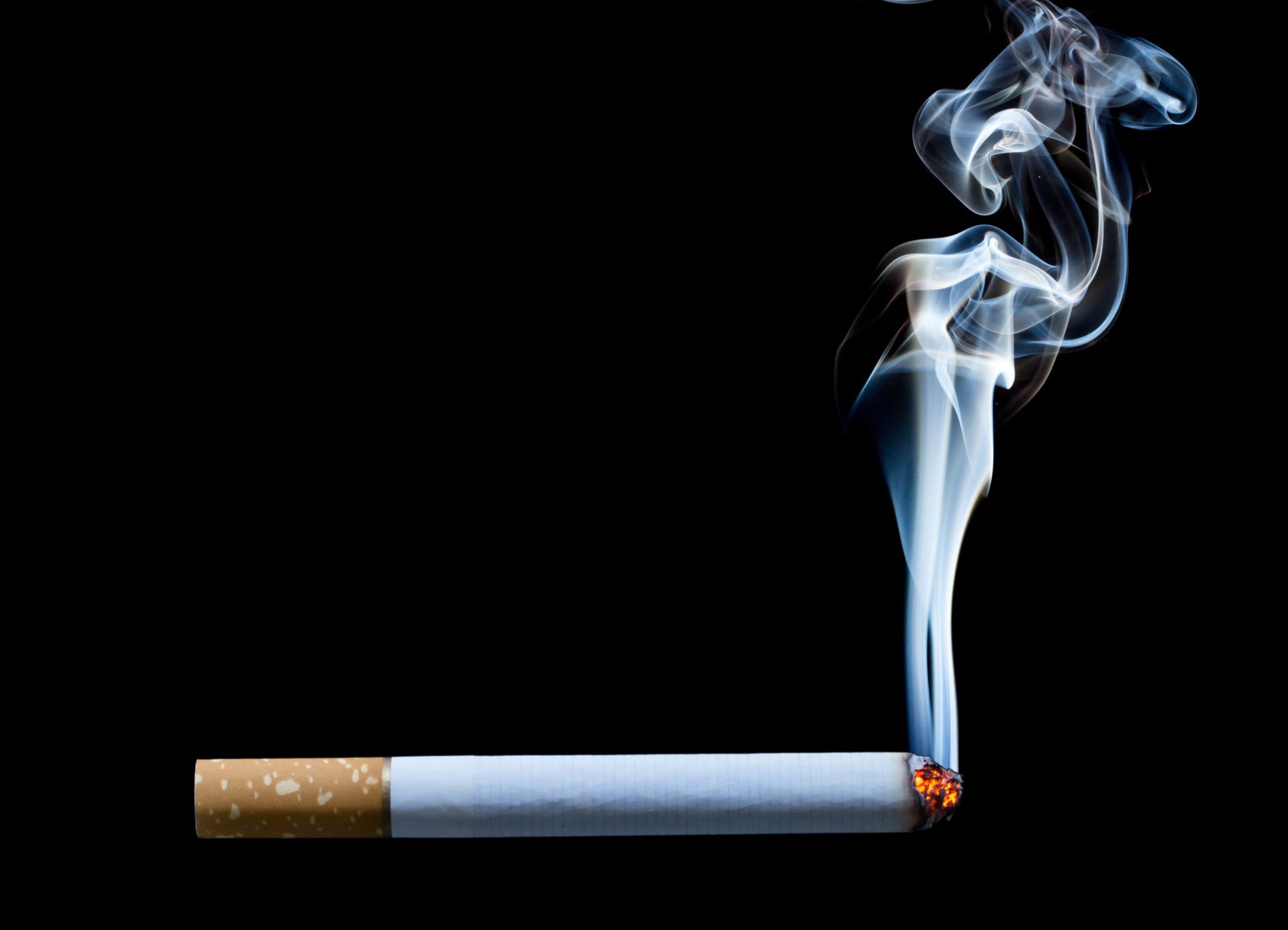lit cigarette burning with a black background